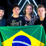 Integrantes do 5 Seconds of Summer segurando a bandeira do Brasil