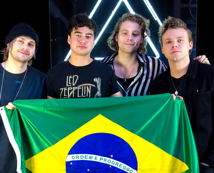 Integrantes do 5 Seconds of Summer segurando a bandeira do Brasil